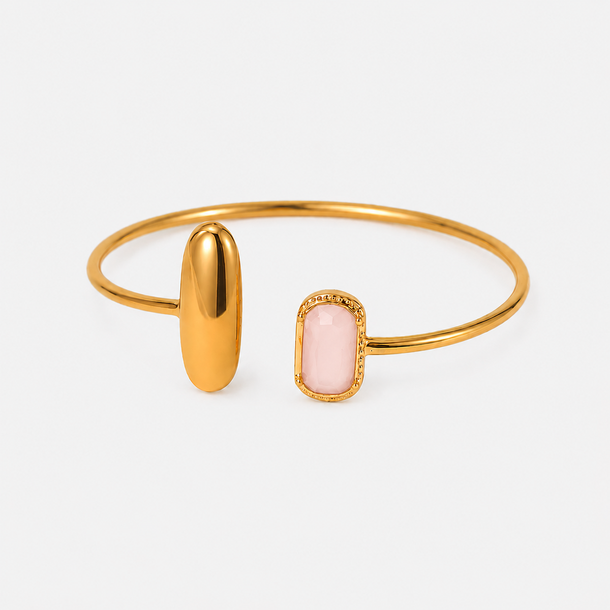 Gold bangle bracelet with a polished oval gold end and a rectangular pink stone bezel-set end, shown on a light gray background.