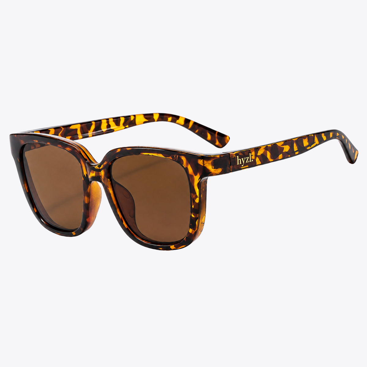 Tortoiseshell sunglasses with brown lenses and a small gold hyzl logo on the temple, shown on a light gray background.