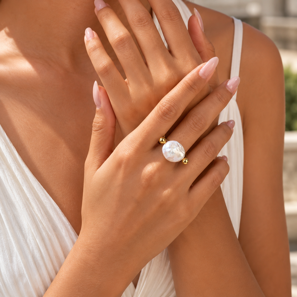 A close-up lifestyle shot of a model wearing a gold ring with a large, round, iridescent white pearl-like stone on one finger.