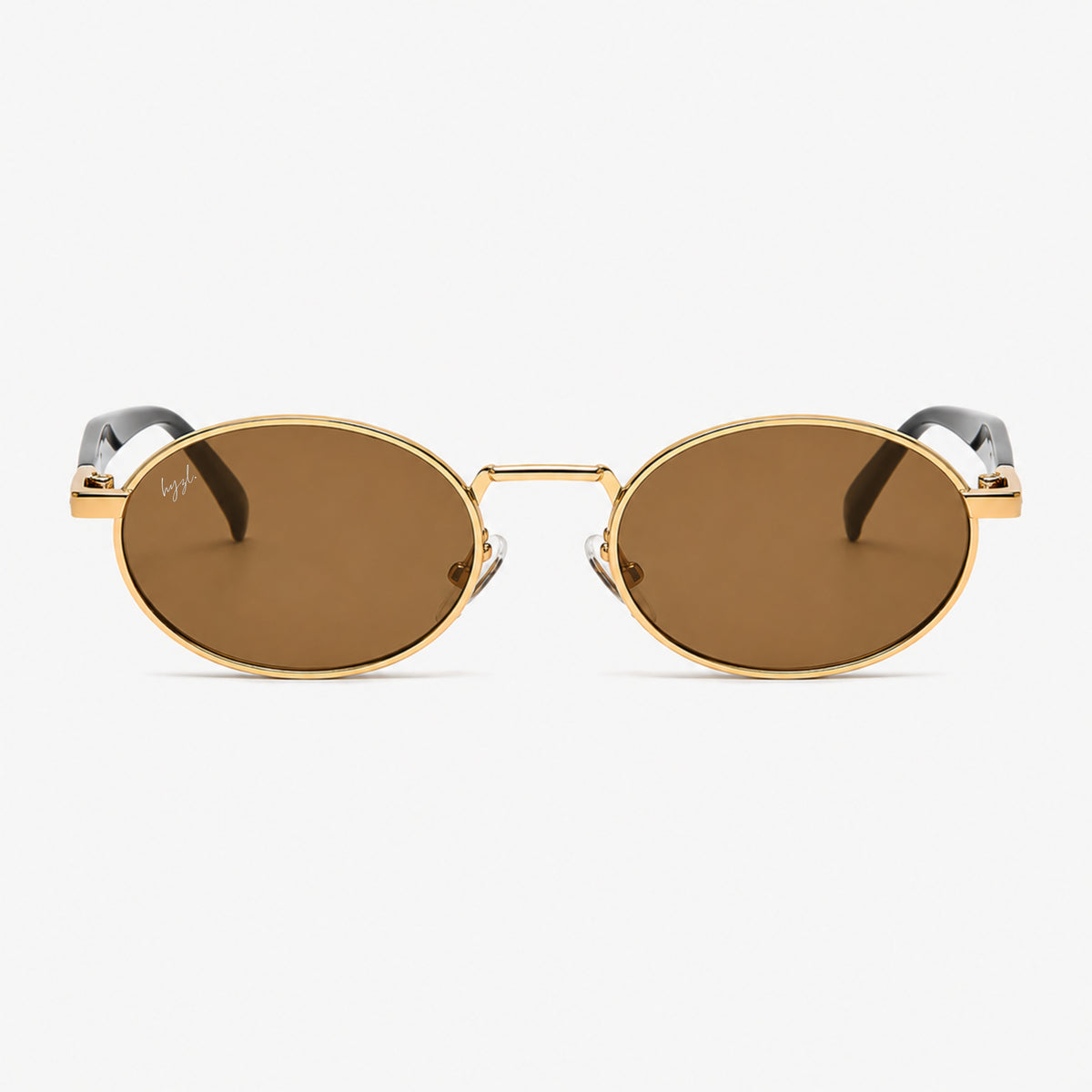 Oval sunglasses with gold metal frames and brown lenses, featuring a thin bridge and dark temple arms, shown against a light gray background.