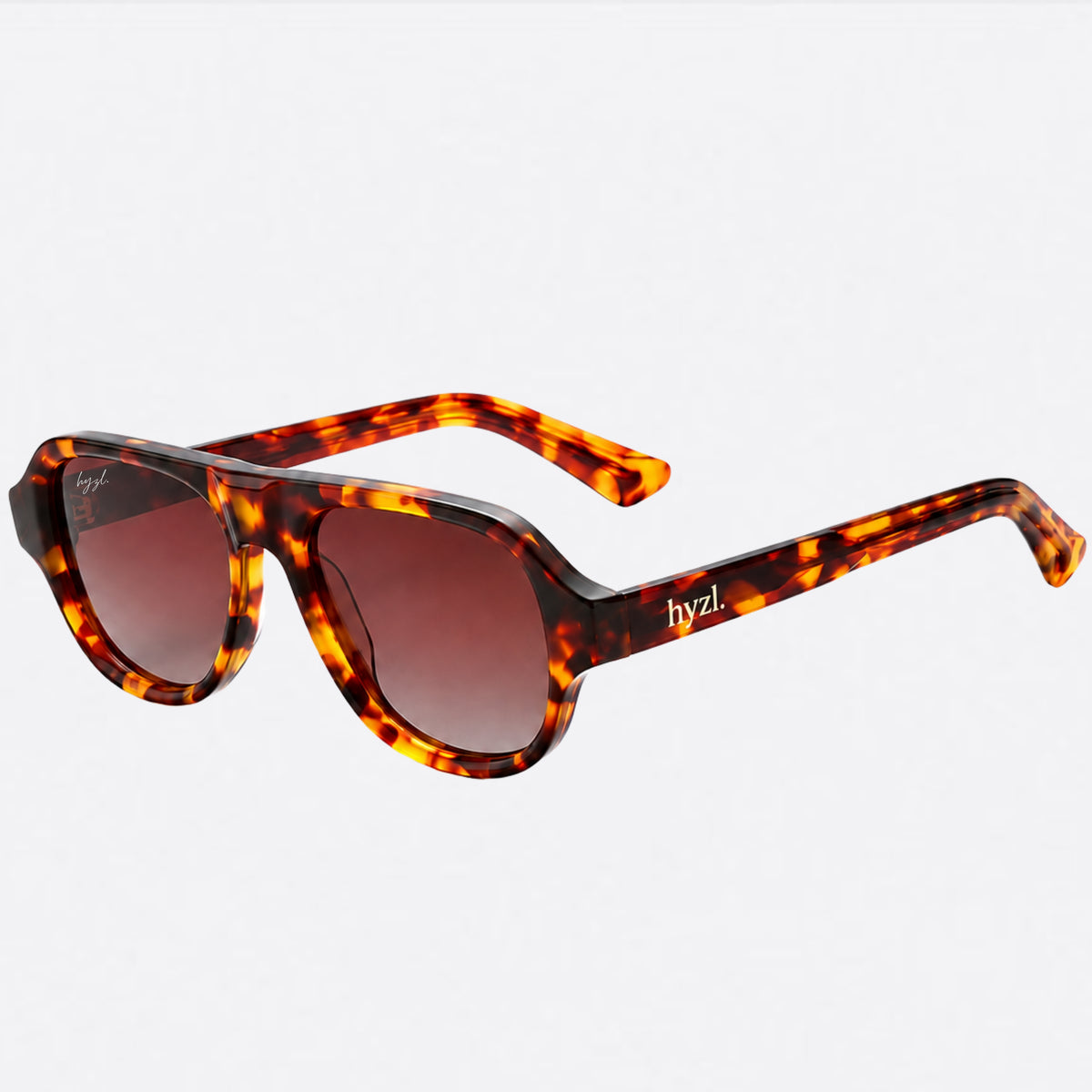 A pair of angular shield-style sunglasses with a glossy tortoiseshell frame in amber, orange, and black, paired with brown gradient lenses. The brand name 'hyzl.