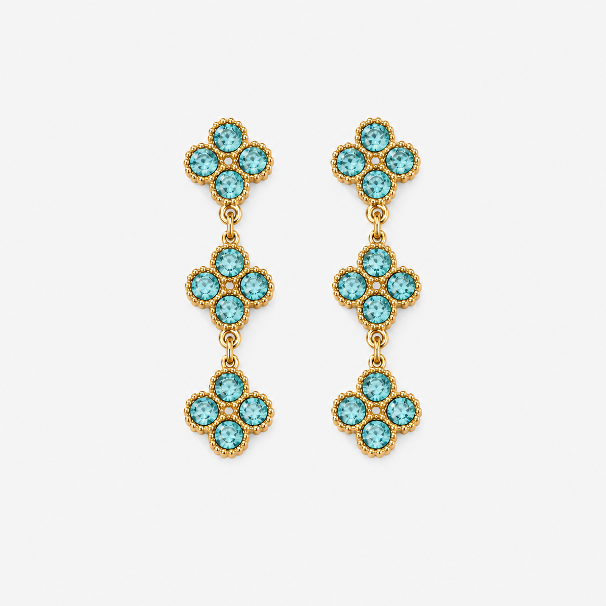 A pair of gold dangle earrings featuring three stacked floral clusters, each adorned with small round turquoise-blue stones in a bezel setting, shown against a light gray background.