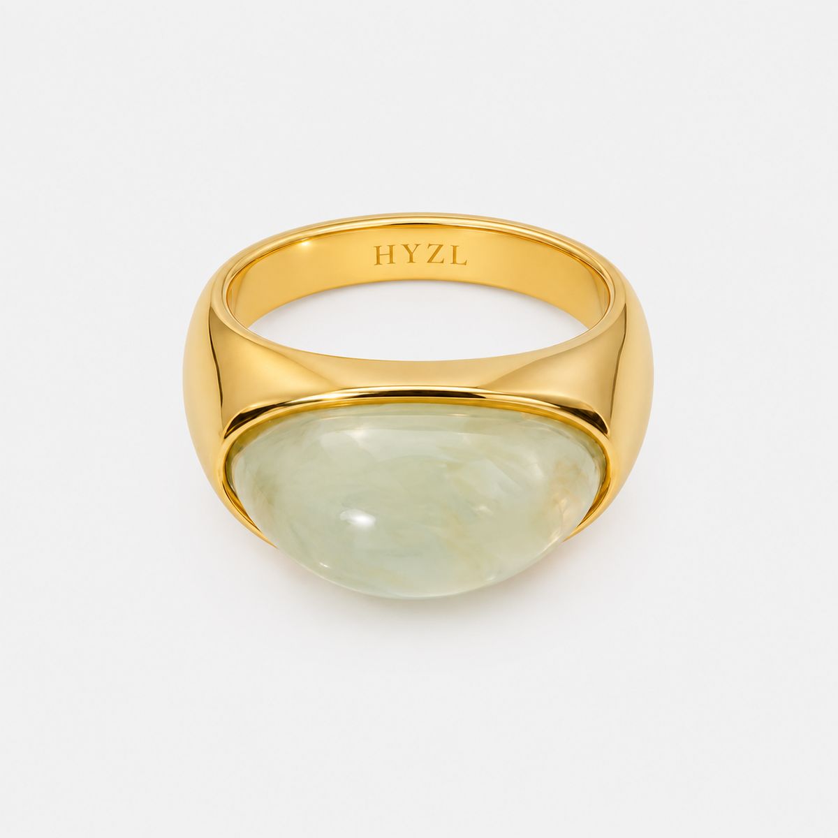 A polished gold signet ring featuring a large, smooth, oval-shaped light green stone, shown on a clean light gray background. The inside of the band is engraved with the brand name 'HYZL'.