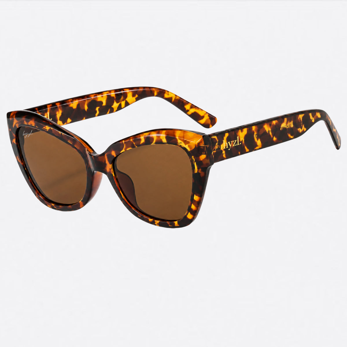 Cat-eye sunglasses with a brown and black tortoiseshell patterned frame and brown lenses, shown on a light gray background.